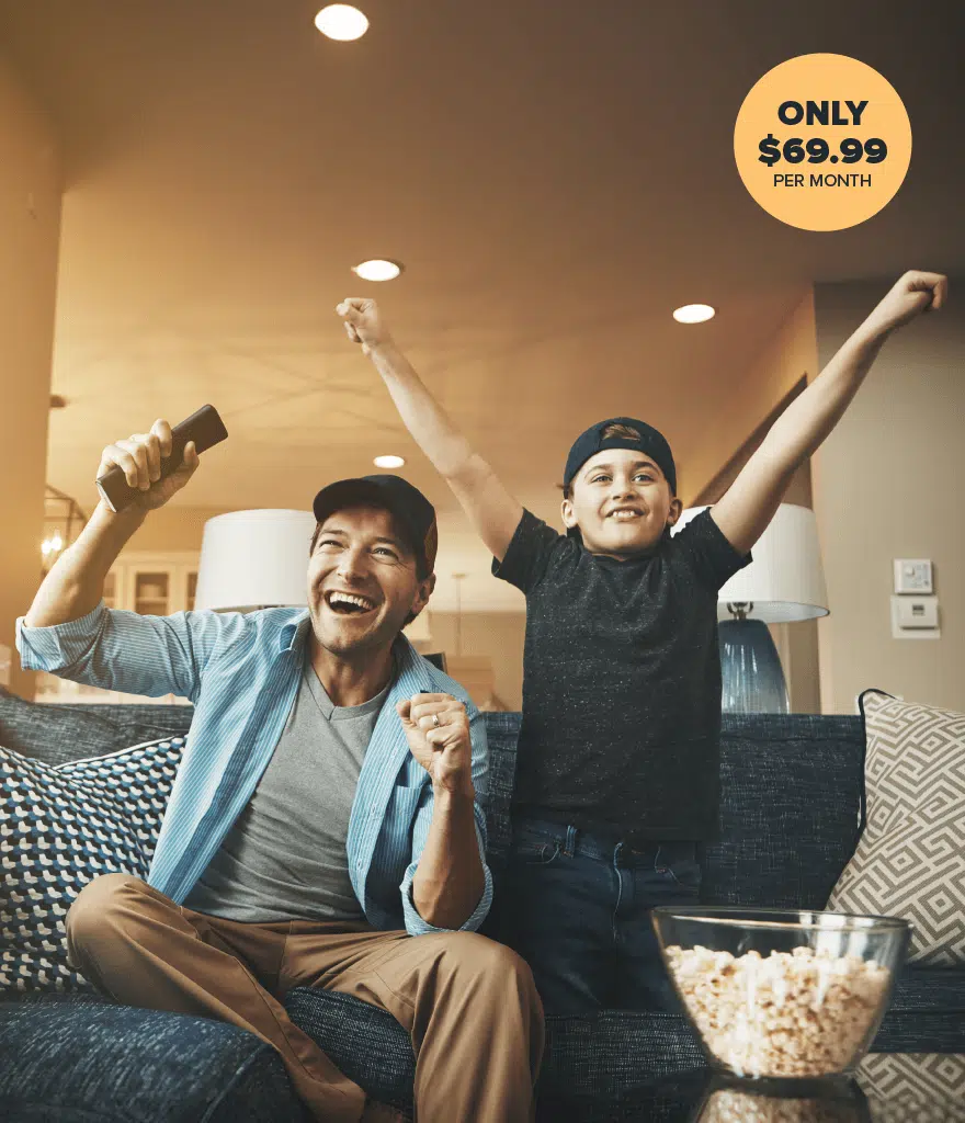 Dad and kid eating popcorn cheering on couch