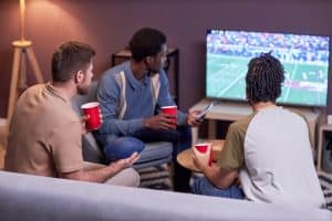 Three guys watching a football game together on the couch.