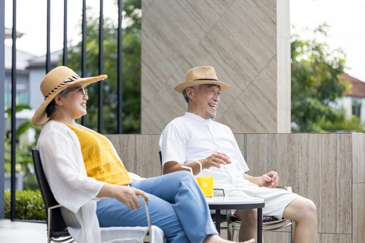Senior Asian couple get refreshment fruit juice by the swimming pool in the tropical resort hotel for summer vacation travel and happy retirement elder for healthy aging activity wellness